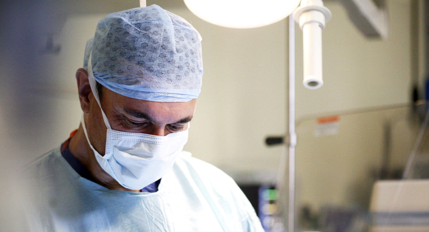 Consultant in operating theatre wearing surgical face mask